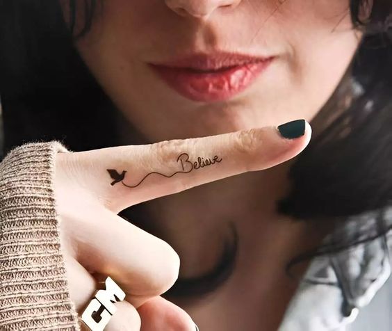 Tatouage Oiseau Noir Et Mot Believe Sur Le Doigt